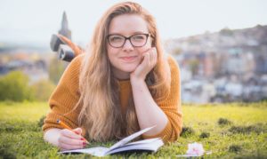 Student with notebook laying in grass field